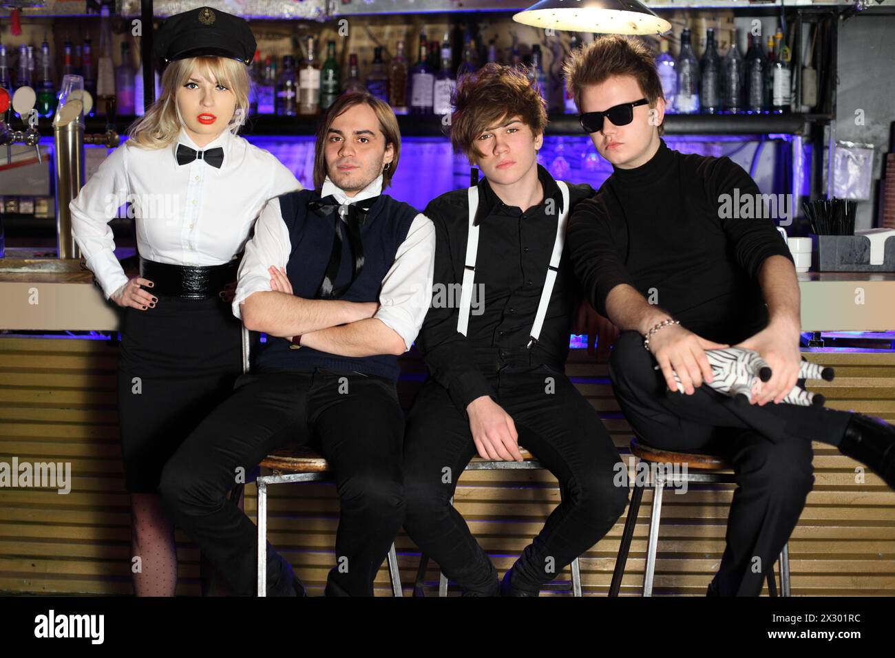Vier junge Rockbands in Schwarz-weiß-Posen in der Nähe der Bartheke. Stockfoto