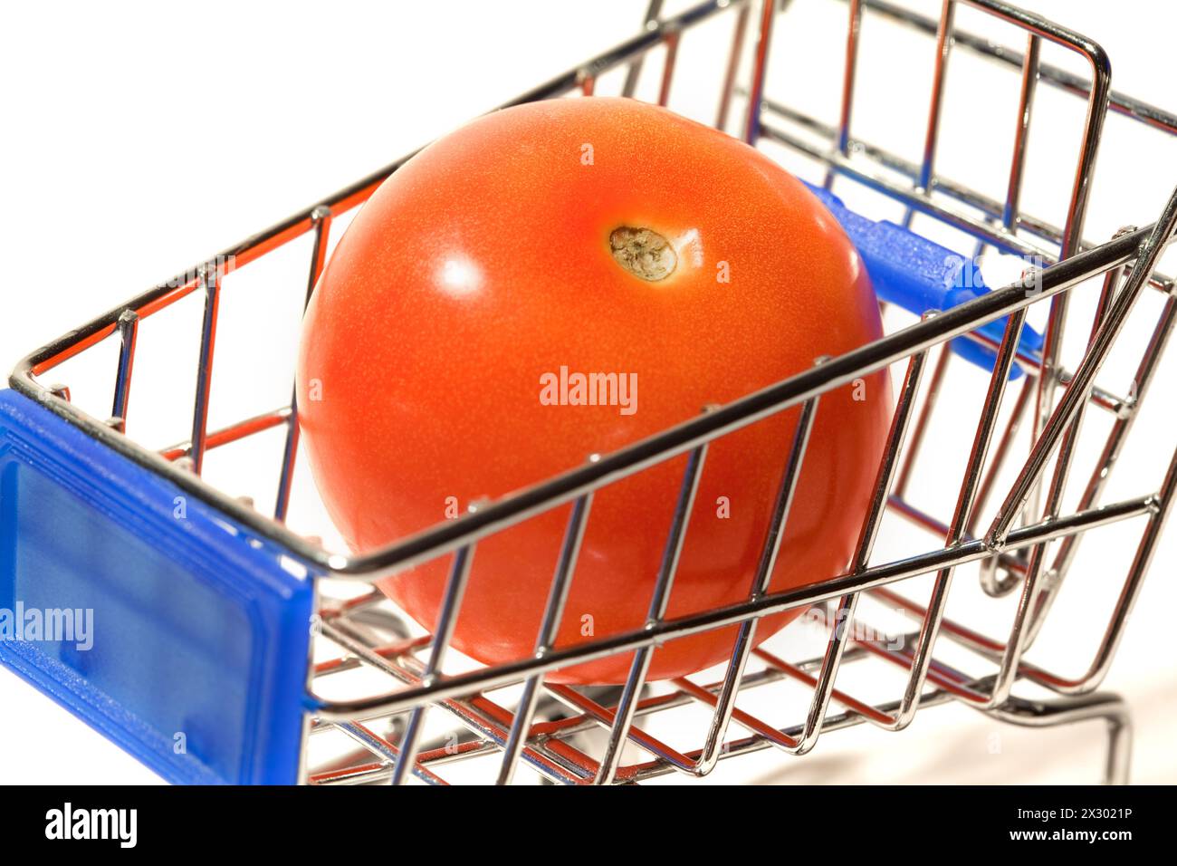 Eine große rote Tomate in einem kleinen Einkaufswagen, isoliert auf weißem Hintergrund Stockfoto