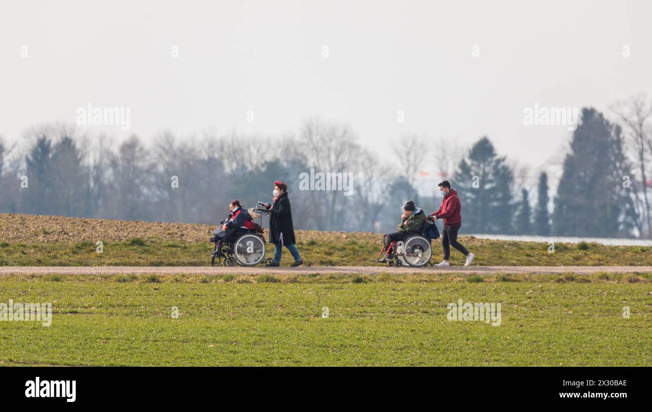 Zürich, Schweiz - 12. März 2022: Betreuer sind mit Menschen mit einer körperlichen Beeinträchtigung mit dem Rollstuhl unterwegs. Die ersten wärmenden Stockfoto