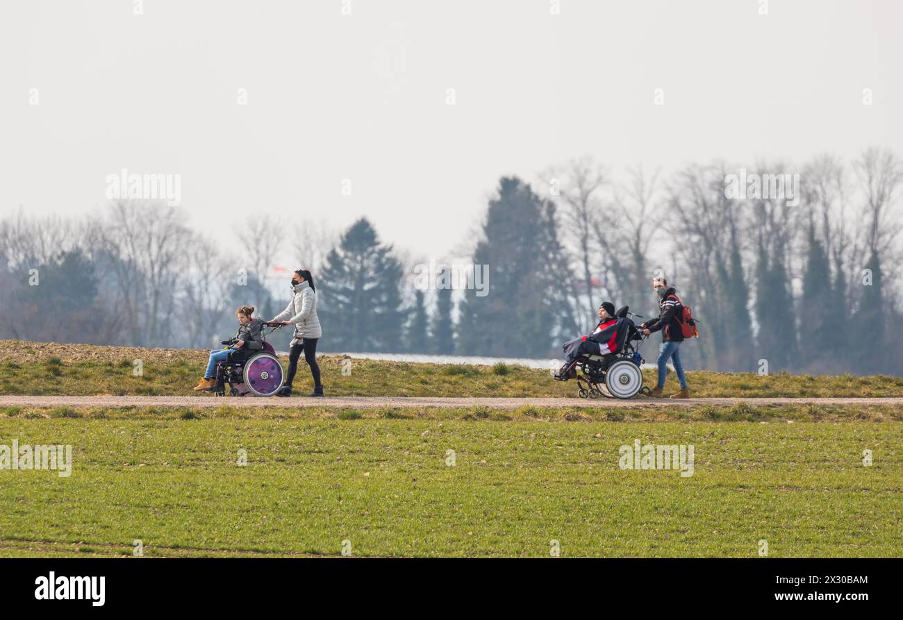Zürich, Schweiz - 12. März 2022: Betreuer sind mit Menschen mit einer körperlichen Beeinträchtigung mit dem Rollstuhl unterwegs. Die ersten wärmenden Stockfoto