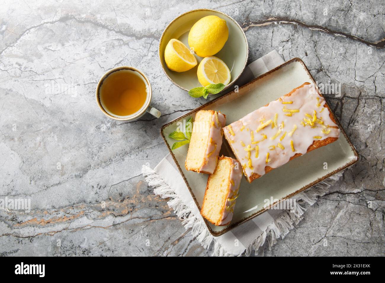 Zitronenstreuselkuchen mit Zitronenschale und Zuckerguss ist ein klassischer britischer Tee-Leckerbissen auf dem Teller auf dem Tisch. Horizontale Draufsicht von oben Stockfoto