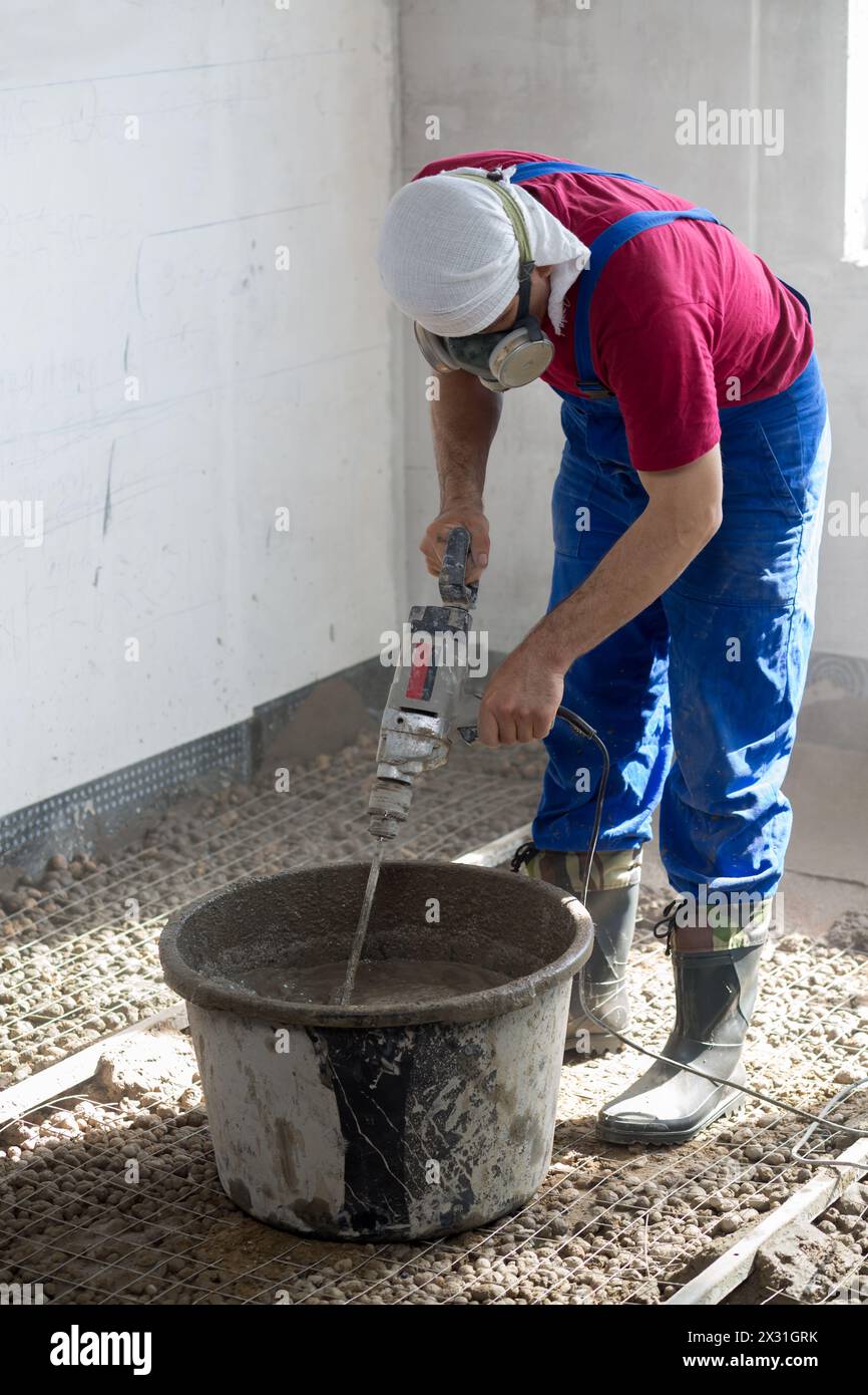 Der Arbeiter bereitet die Mischung zum Ausgießen des Bodens vor Stockfoto