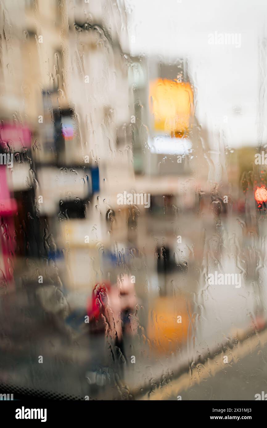 Vertikale Aufnahme an einem regnerischen Tag in Liverpool, gesehen durch das regnerische Fenster eines Doppeldeckerbusses. Nicht erkennbare Leute, die auf den Bus warten Stockfoto