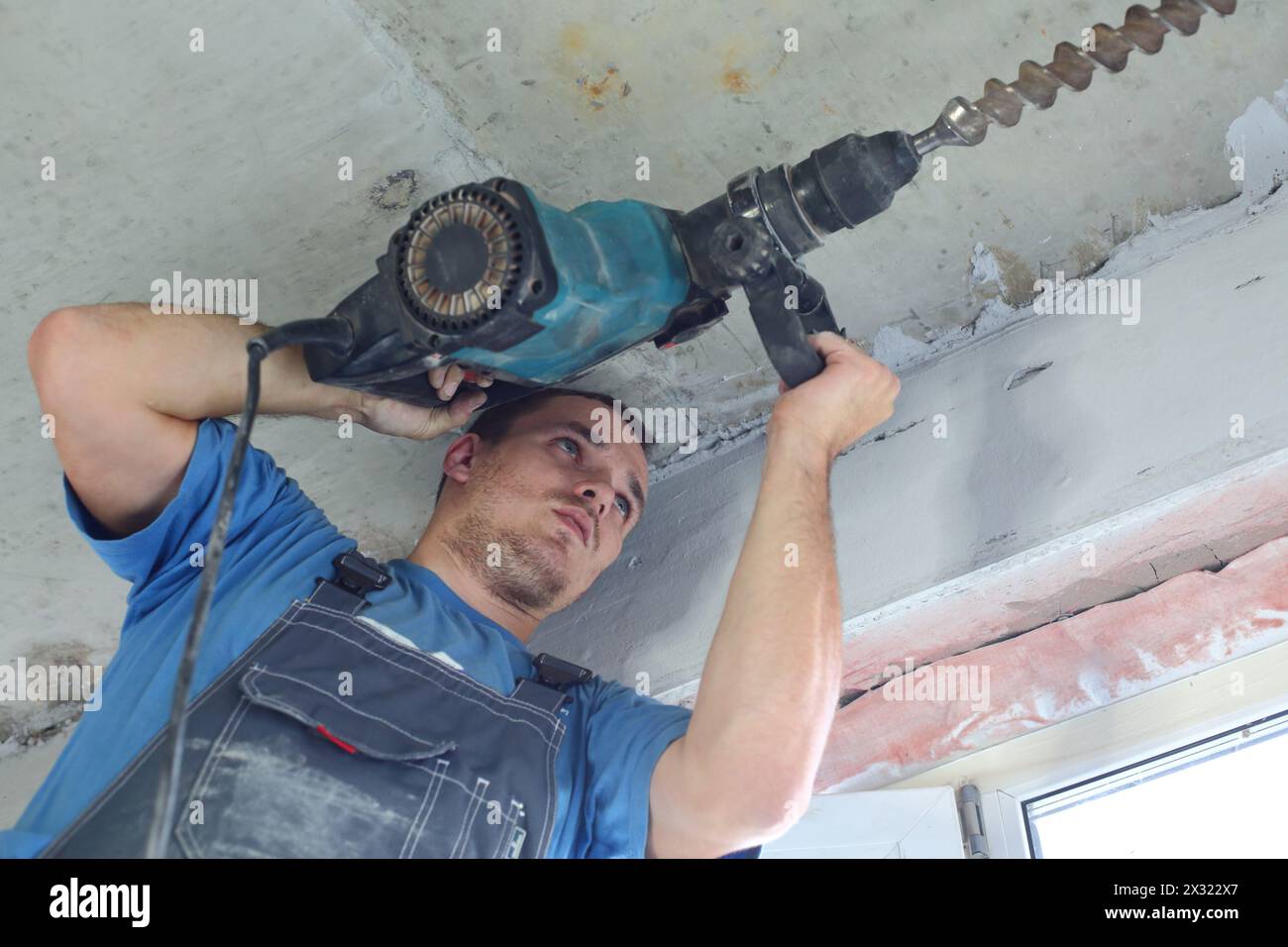 Der Arbeiter in Arbeitskleidung, der mit einem großen Perforator arbeitet Stockfoto