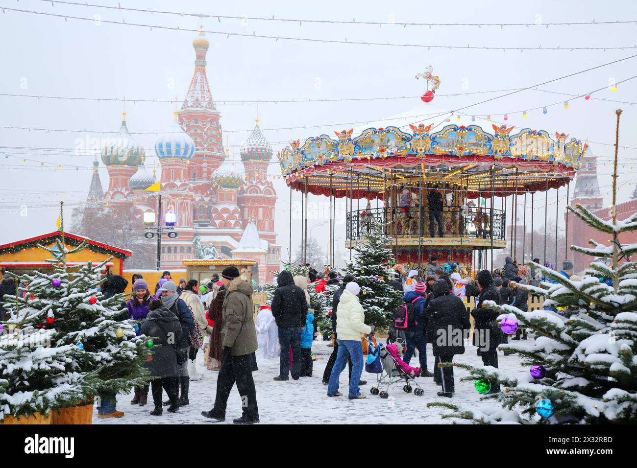 MOSKAU, RUSSLAND - 8. Dezember 2013: Menschen laufen in der Nähe von Karussell und St. Basilius Kathedrale während der Weihnachtsmesse (Messefläche ca. 2.000 qm) Stockfoto