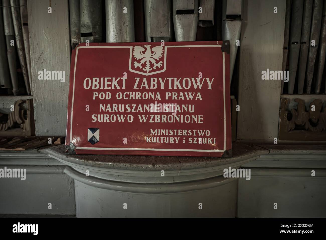 Metallschild mit weißem Polnisch-Schriftzug auf rotem Hintergrund, das besagt, dass das geschützte Denkmal unter dem Schutz des Gesetzes steht. Stockfoto