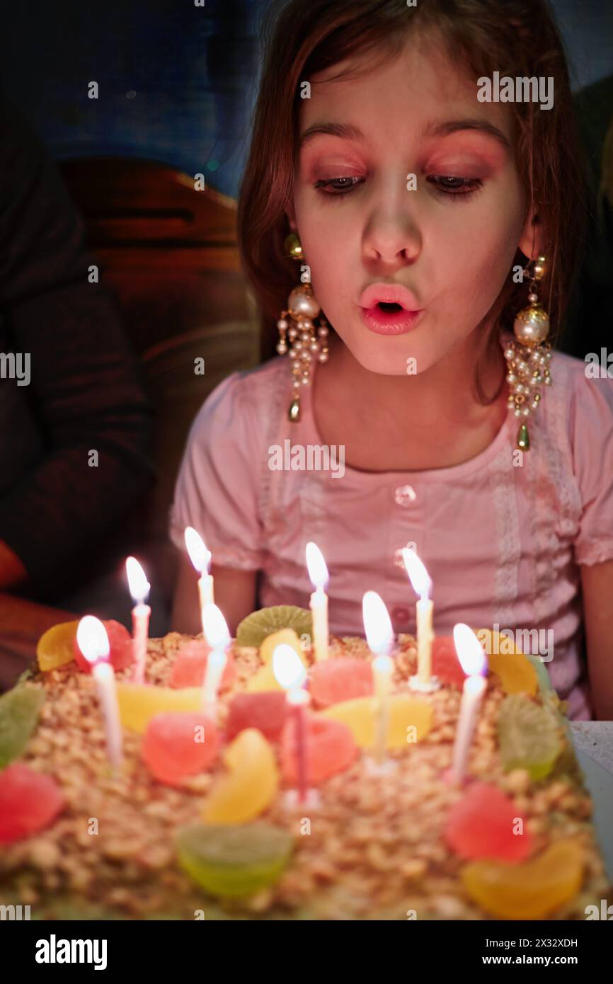 Das kleine Mädchen bläst Kerzen auf der Geburtstagskuche aus Stockfoto