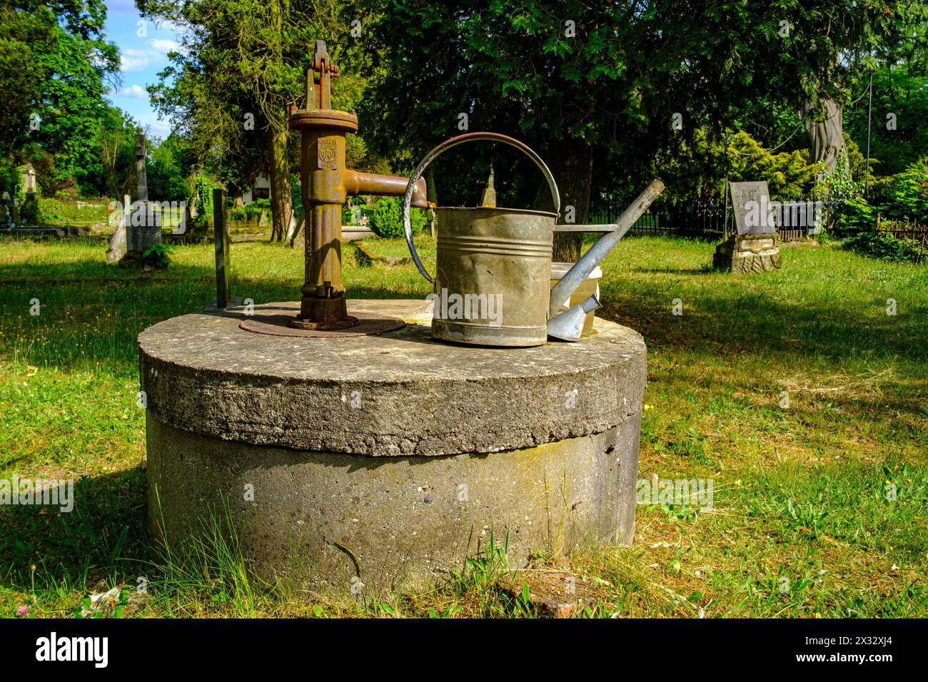 Friedhofromantik mit einer gebeulten Gießkanne auf einem handgepumpten Brunnen, protestantischer Friedhof von Pokoj, Bezirk Namyslow, Woiwodschaft Oppeln, Polen. Stockfoto