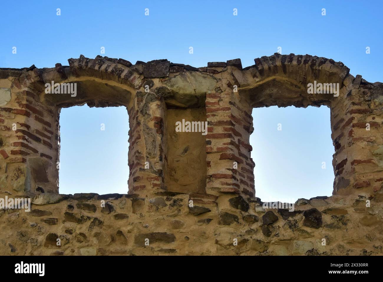 Blick auf den blauen Himmel durch bogenförmige Fenster eines Schlupflochs in der Mauer einer alten Festung. Kopierbereich. Selektiver Fokus. Stockfoto