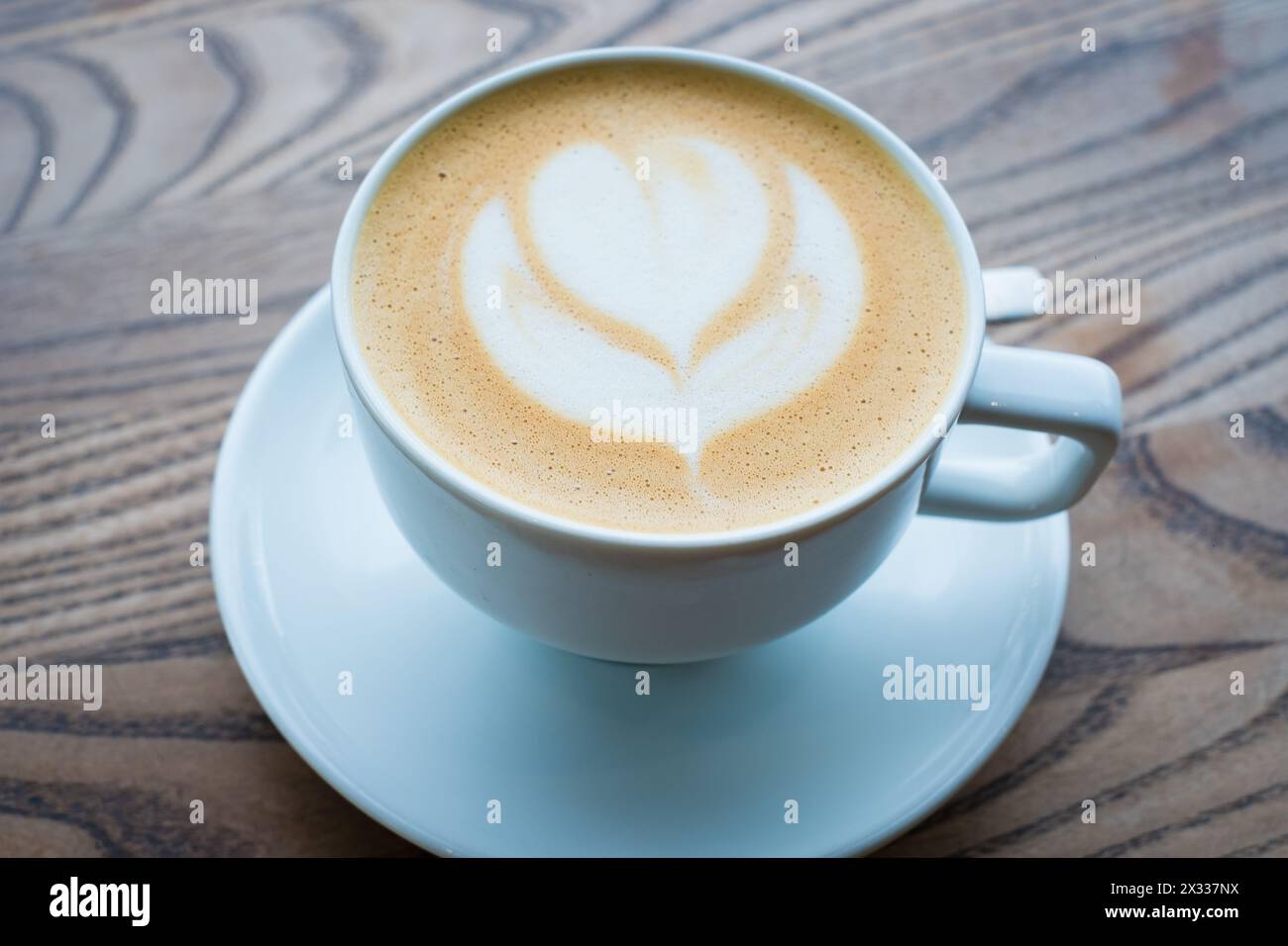 Schöne Tasse Cappuccino mit Hafermilch auf Holztisch. Leerer Kopierbereich für Logo. Stockfoto