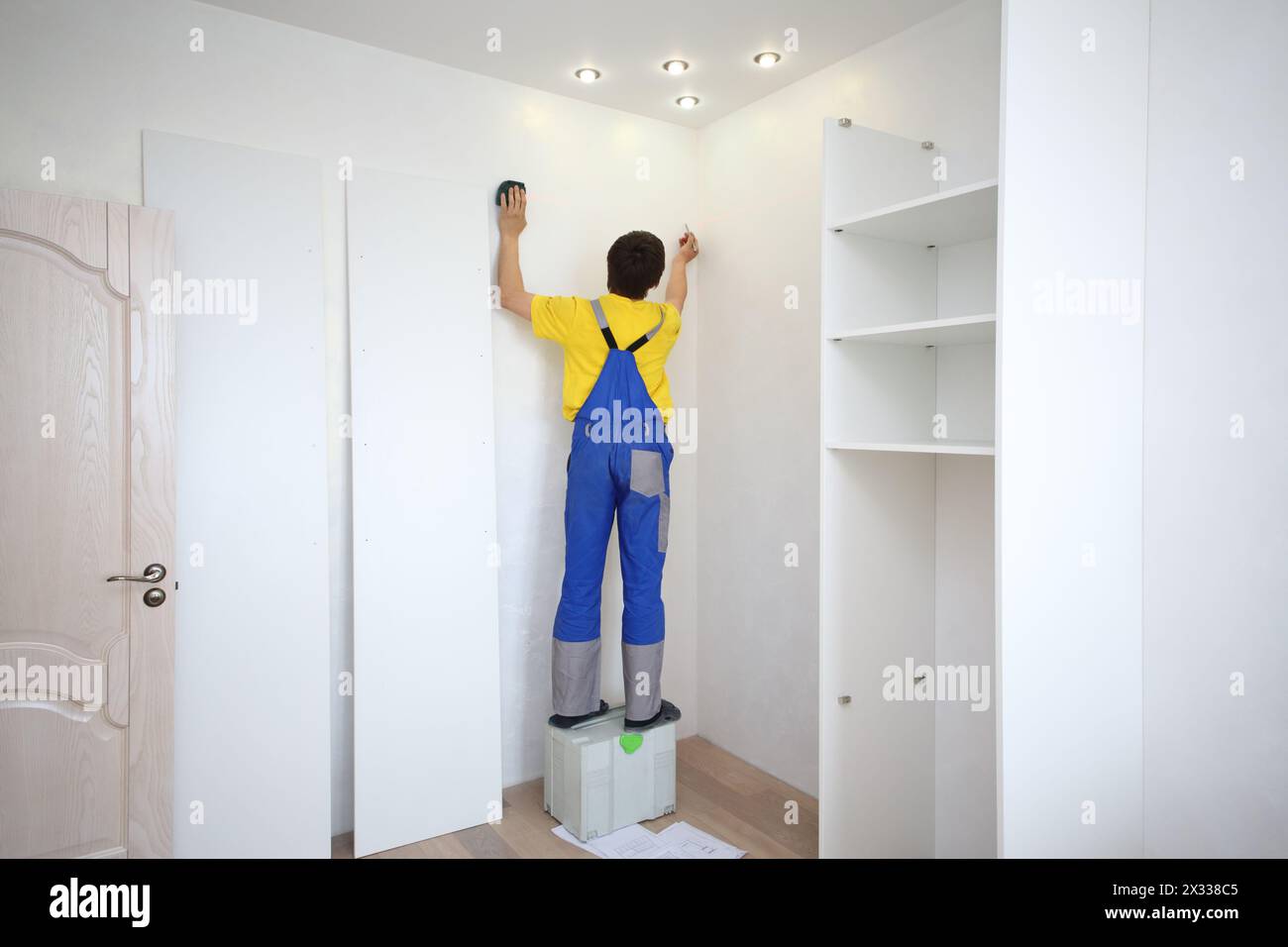 Man macht eine Markierung an der Wand, um einen Eckschrank zu installieren Stockfoto