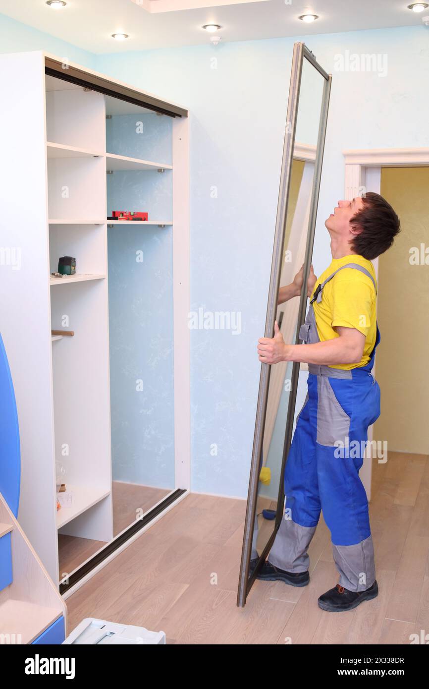 Arbeiter stellen eine Tür für einen Schiebetür in einem Zimmer mit blauen Wänden ein Stockfoto