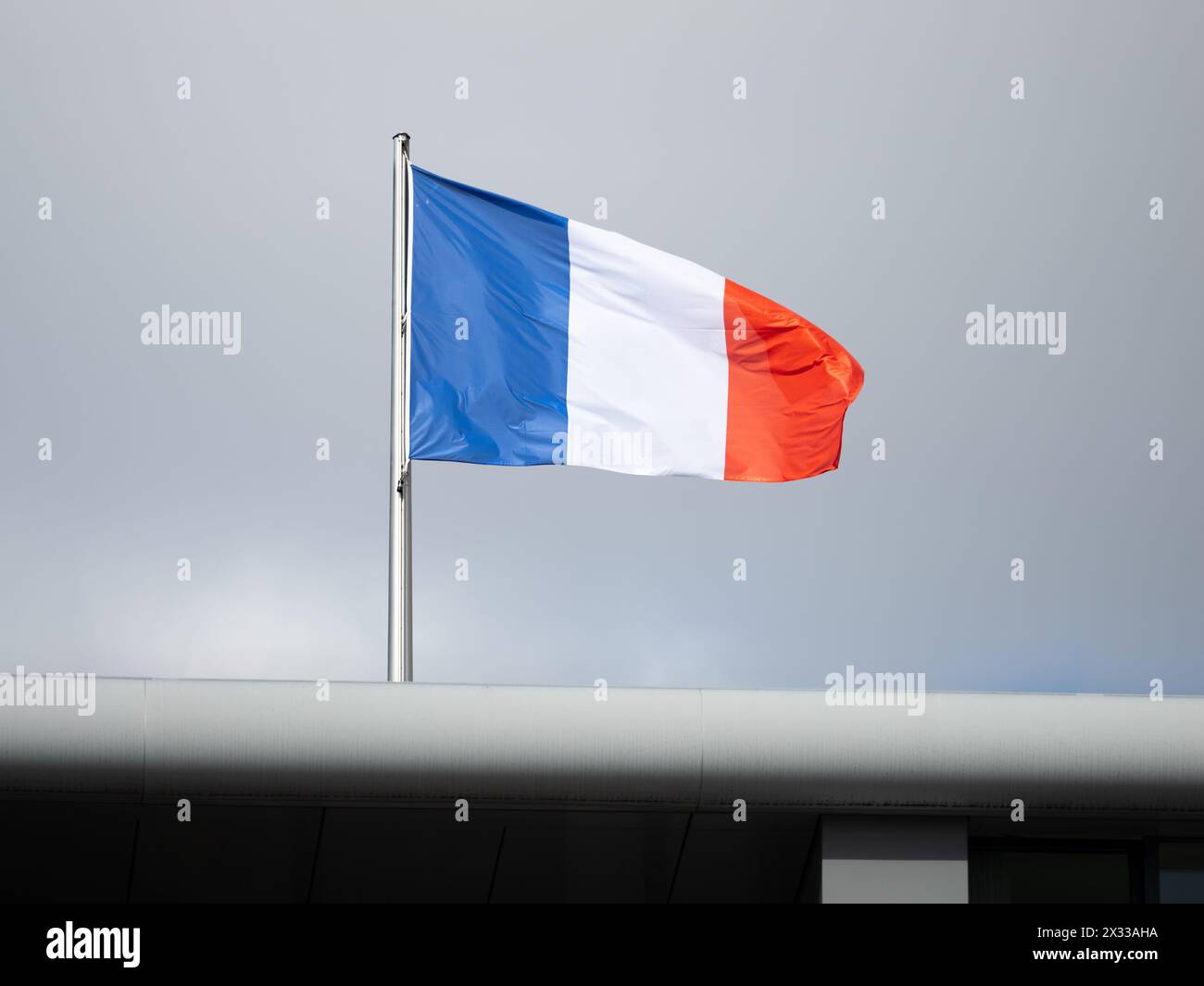 Die Flagge Frankreichs auf einem Gebäude. Der dunkle Himmel ist im Hintergrund. Das Symbol des Stolzes und des Patriotismus ist Teil der französischen Identität. Stockfoto