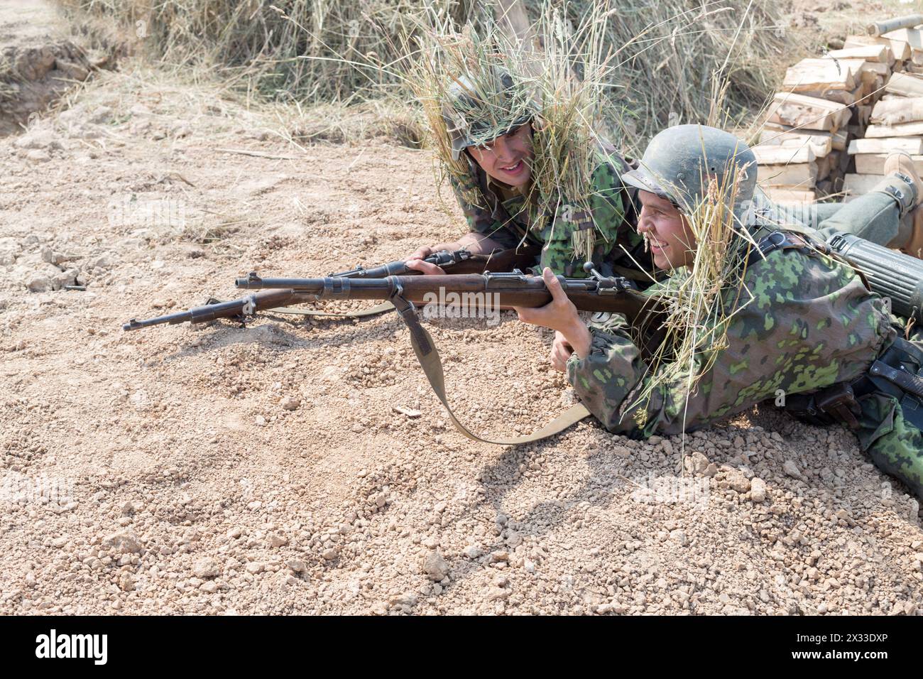 NELIDOVO, RUSSLAND – 12. JULI 2014: Schlachtfeld 2014: Zwei Nazi-Soldaten lachen mit Gewehren im Graben Stockfoto