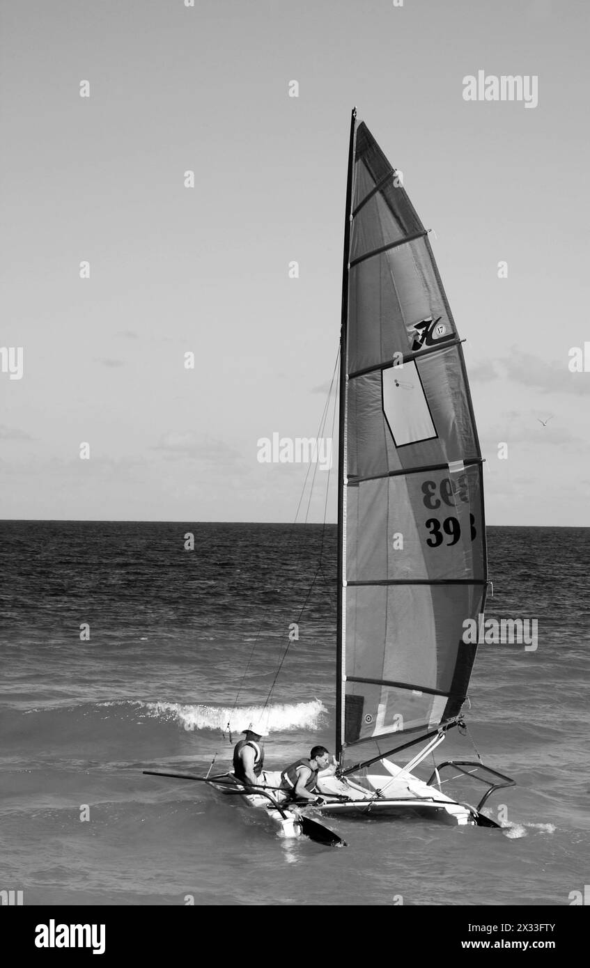 Zwei Männer starten ein Segelboot von der Küste in Fort Lauderdale, Florida, USA. Stockfoto
