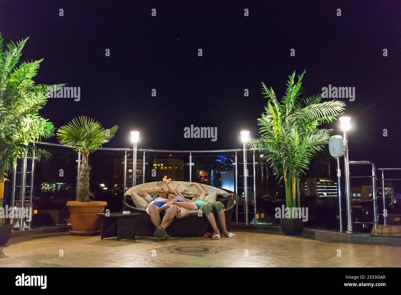 Vater und zwei Kinder schlafen nachts auf einer Korbcouch auf dem Dach des Hotels Stockfoto