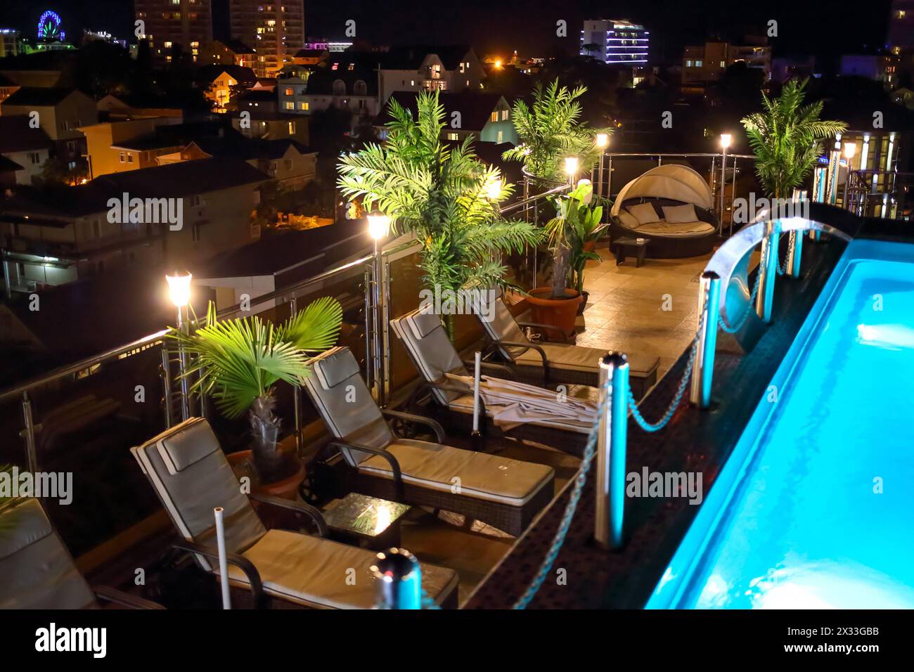 Swimmingpool und Liegestühle auf dem Dach des Hotels in der Nacht Stockfoto