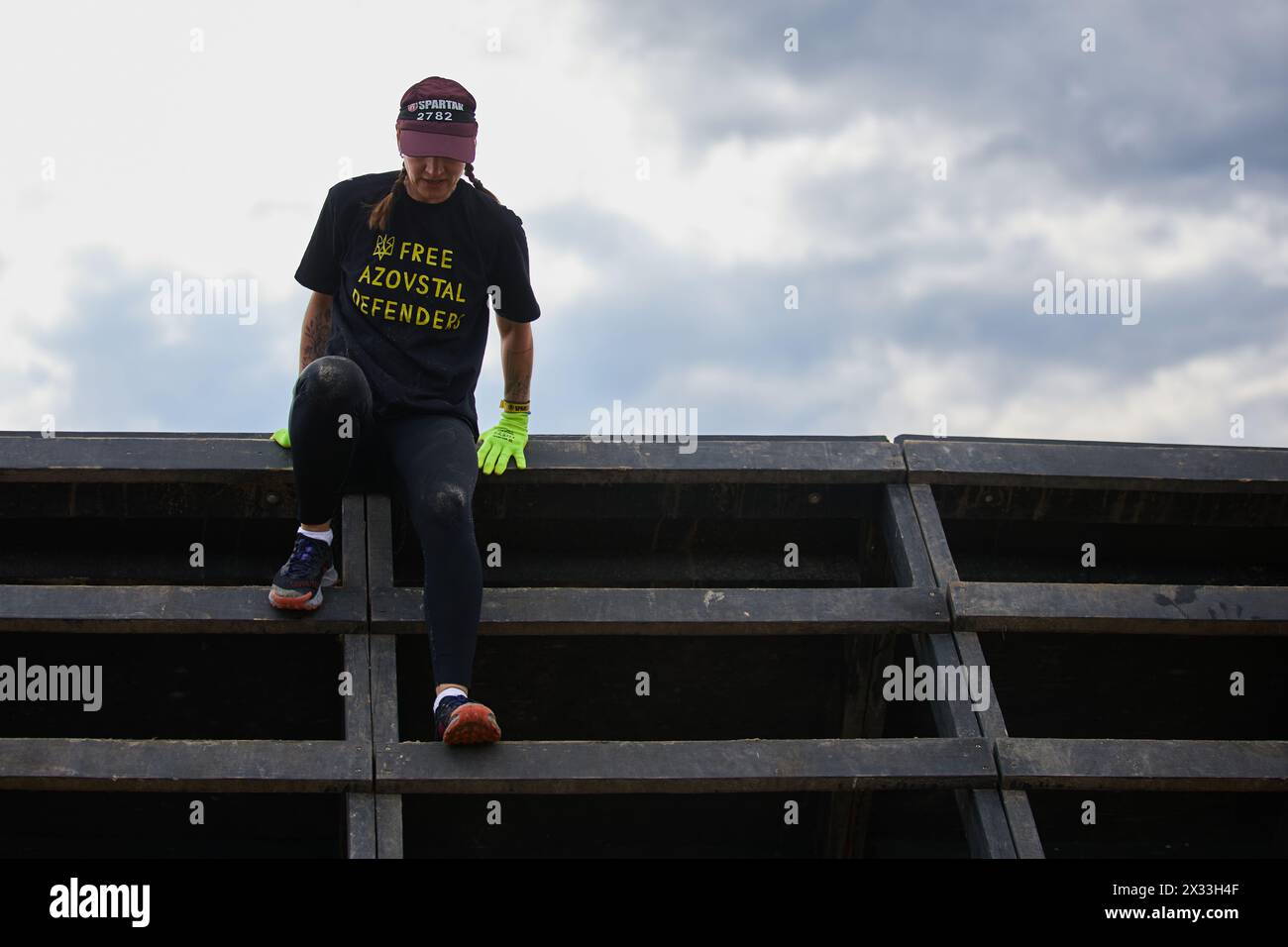 Beim Spartan Race Competition in Kiew am 20. April 2024 klettert eine Sportlerin über die Rutschwand Stockfoto