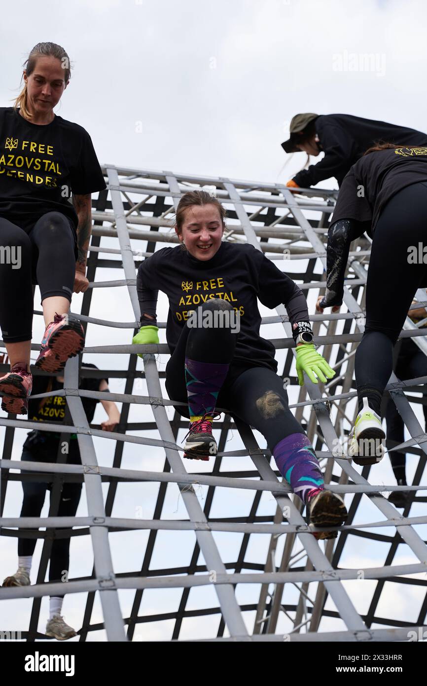 Frauen, die beim Spartan Race Competition in Kiew am 20. April 2024 in einer „A-Frame Cargo“-Disziplin über die große Pyramide klettern Stockfoto