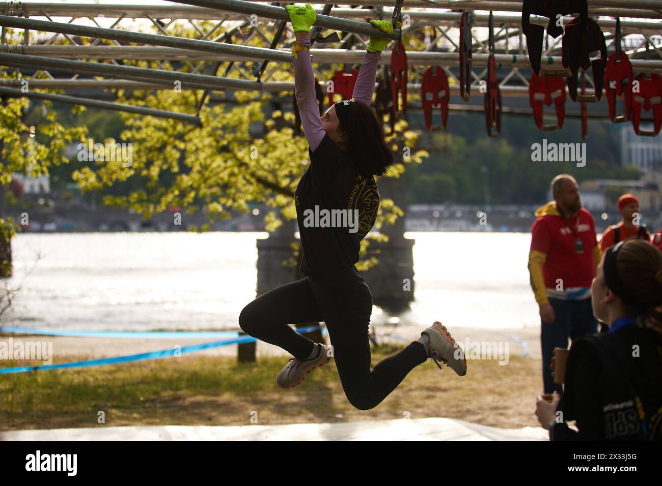 Junge Frau läuft auf horizontalen Gittern während des Affen im Mittelkurs beim Spartan Race Competition in Kiew - 20. April 2024 Stockfoto