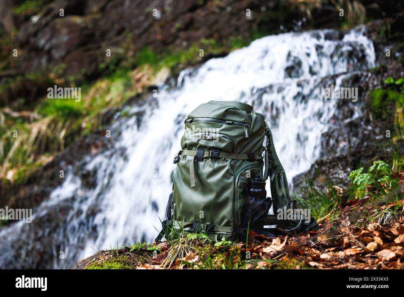Wanderrucksack aus wasserdichtem Stoff im Wald am Fluss in der Nähe des Wasserfalls. Trekkingausrüstung Stockfoto