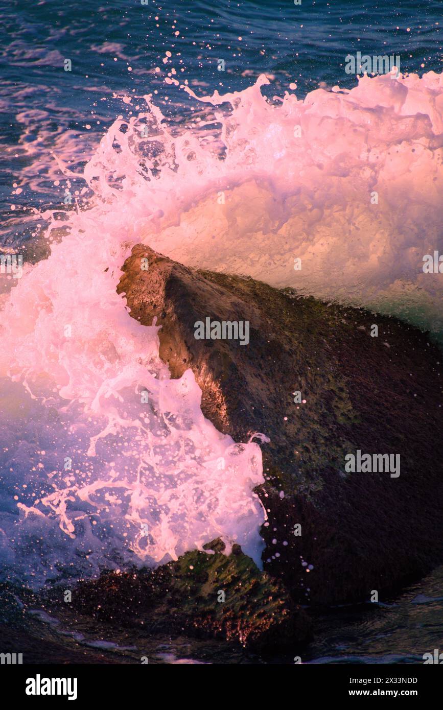 Eine Welle, die bei Sonnenuntergang im Tyrrhenischen Meer in der Nähe der toskanischen Küste gegen einen Felsen stürzt Stockfoto