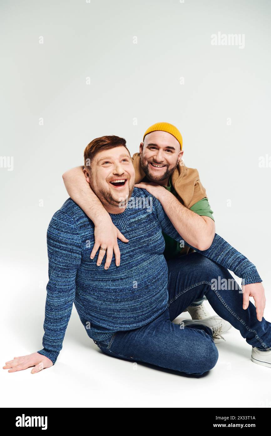 Zwei Männer, einer, der den anderen wiegt, teilen sich einen Moment der Verletzlichkeit und Verbindung. Stockfoto