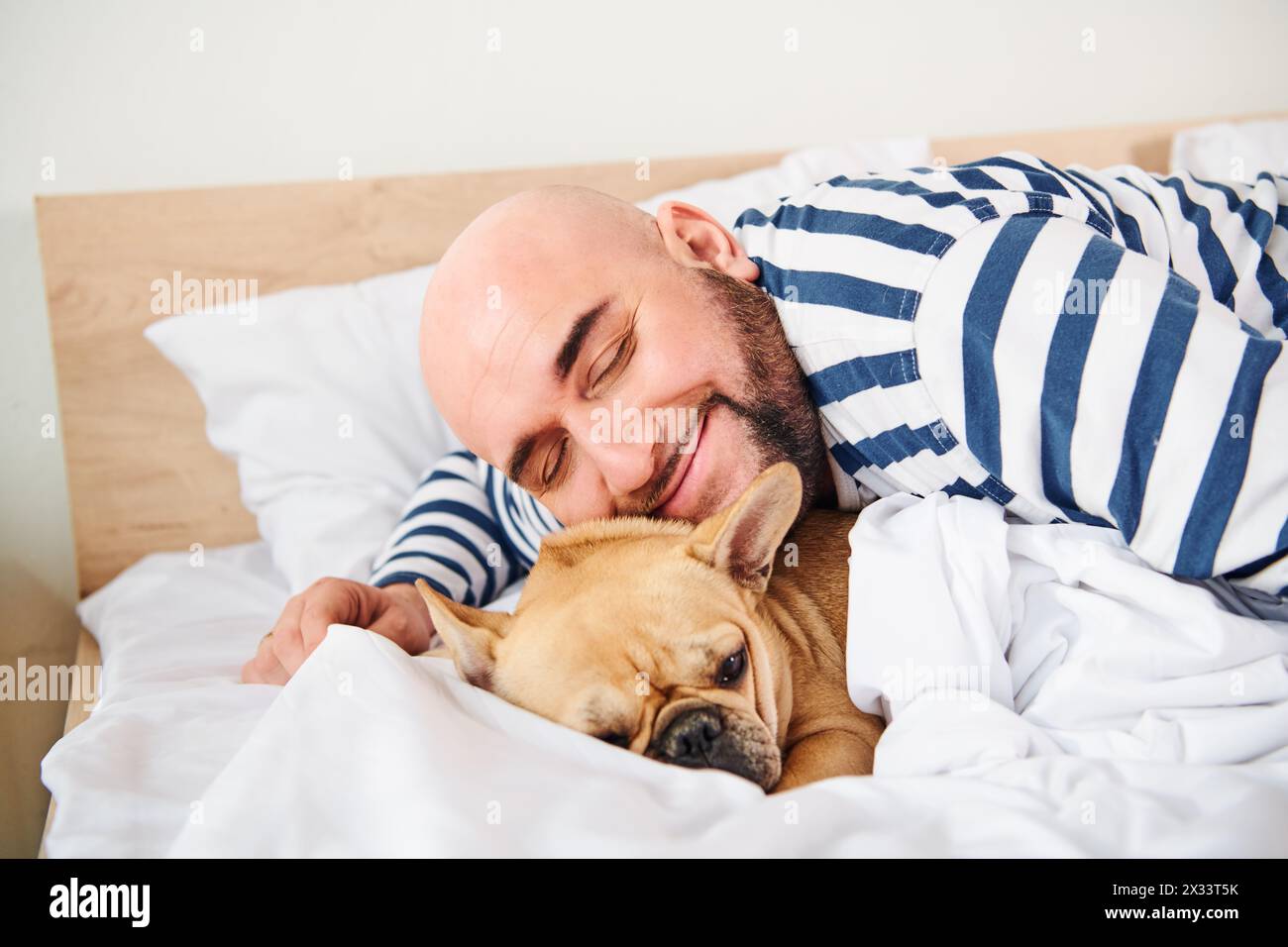 Ein Mann und sein Hund liegen friedlich zusammen im Bett. Stockfoto