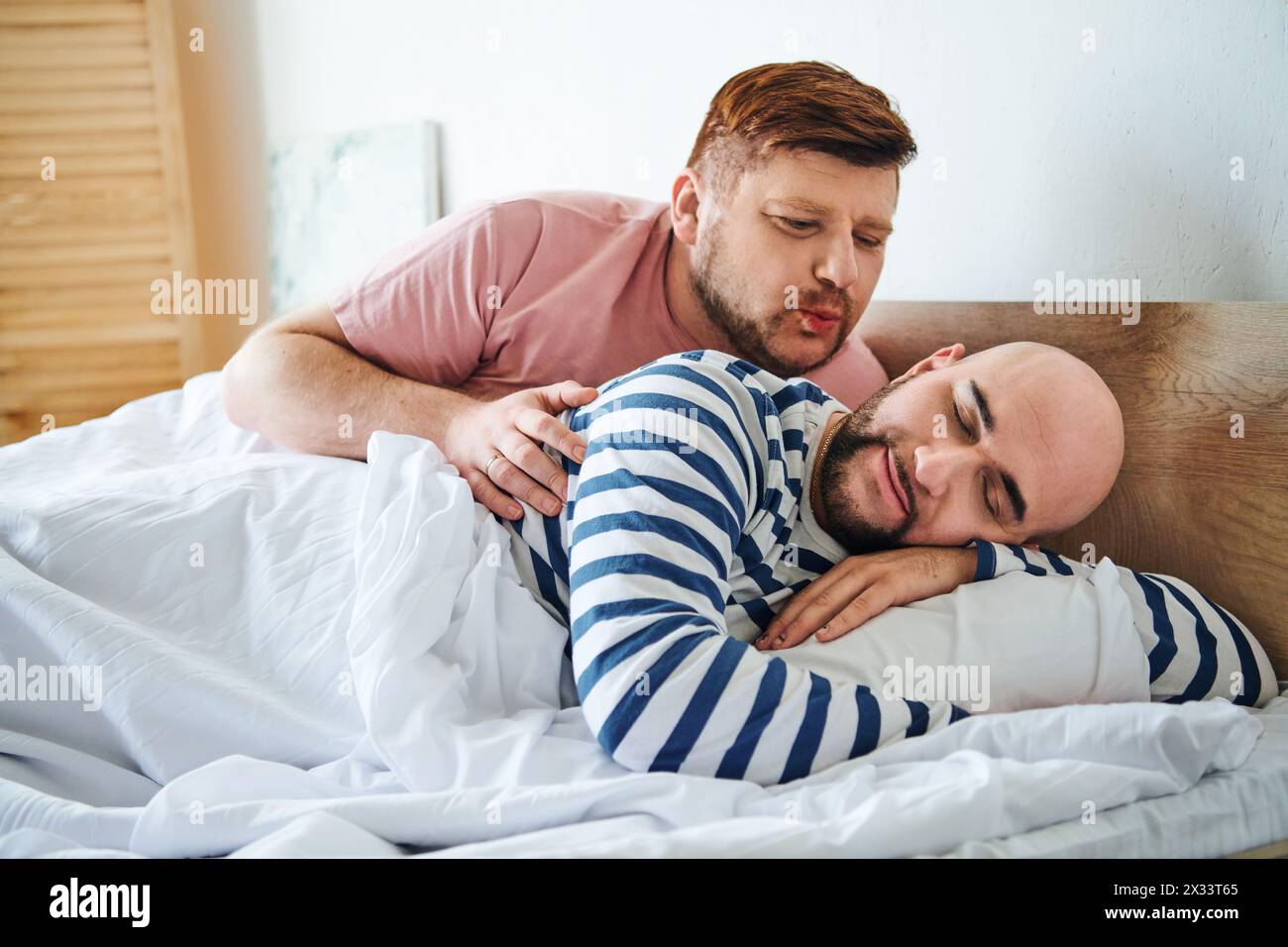 Ein paar Männer liegen friedlich nebeneinander im Bett. Stockfoto
