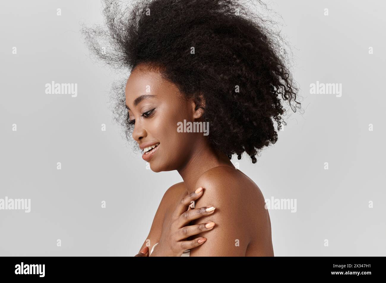 Eine junge Afroamerikanerin mit einem Afro-Lächeln in einem Studio. Stockfoto