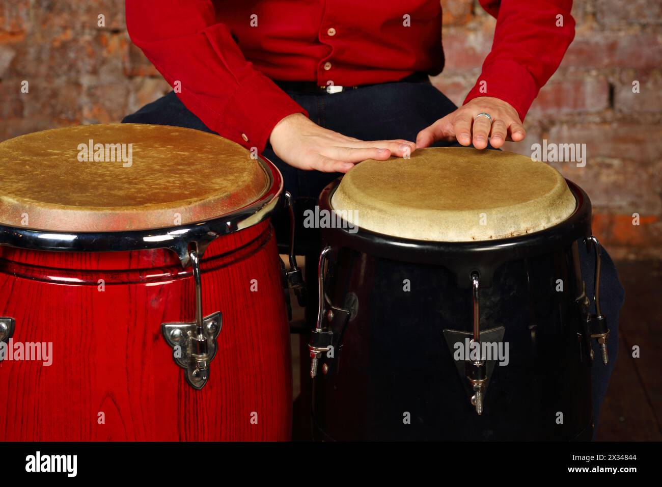 Hände eines jungen Mannes schlagen moderne Trommeln im Studio mit roter Ziegelwand Stockfoto