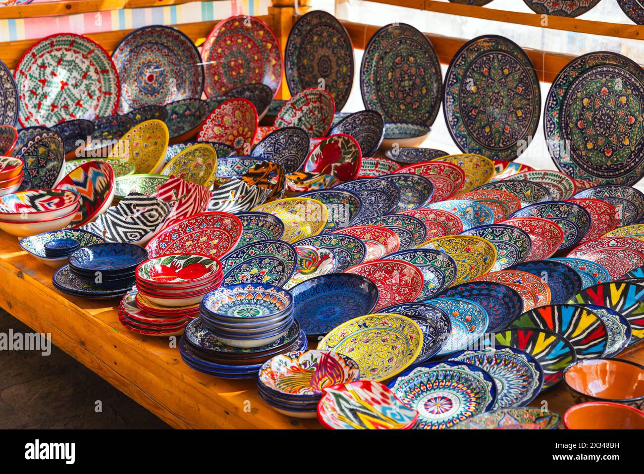 Handgefertigte usbekische Teller und Schüsseln mit bunten traditionellen Mustern werden auf einem Straßenmarkt in Buchara zum Verkauf angeboten Stockfoto