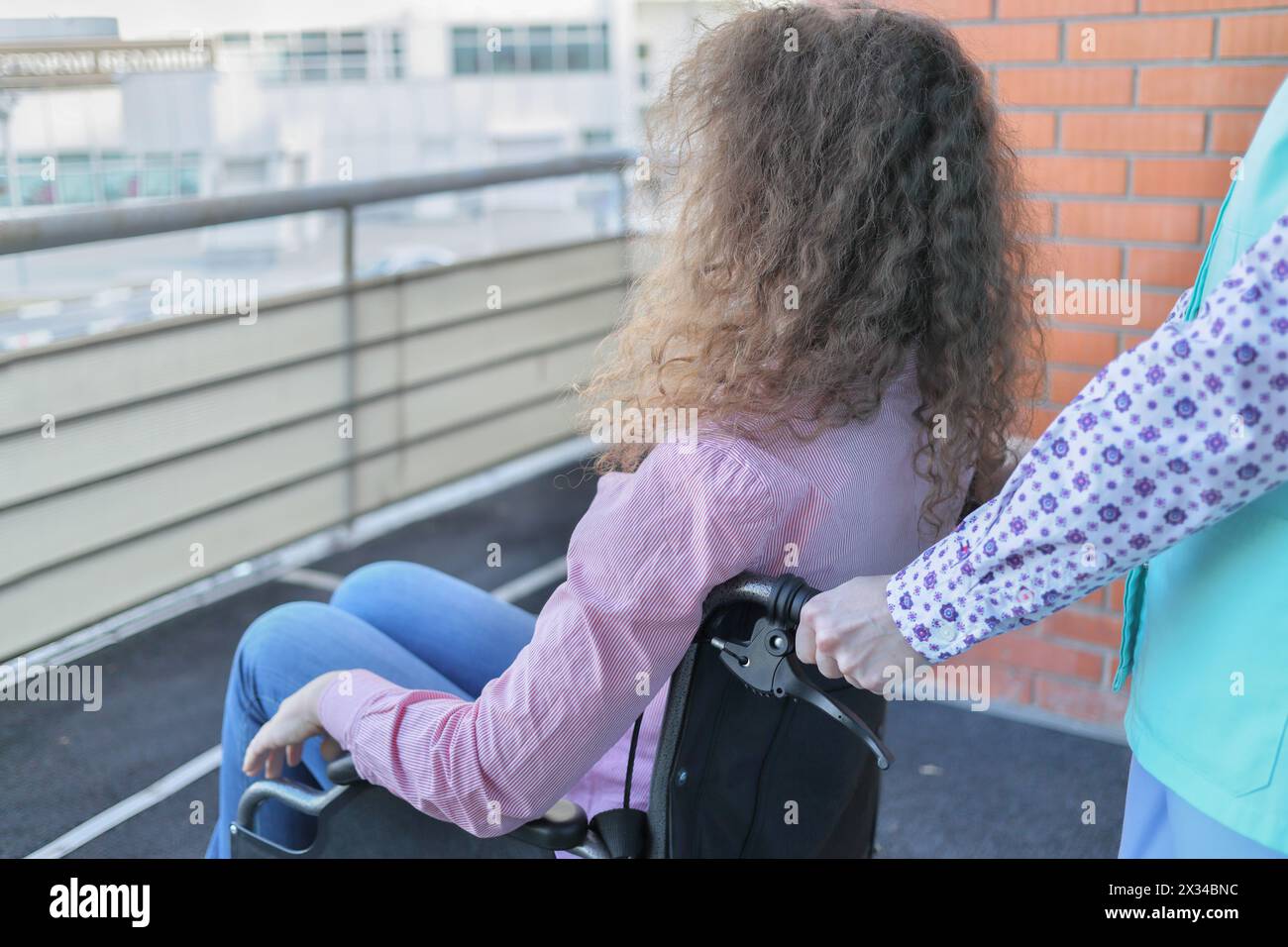 Krankenschwester und Patient im Rollstuhl auf Balkon im Krankenhaus mit frischer Luft Stockfoto