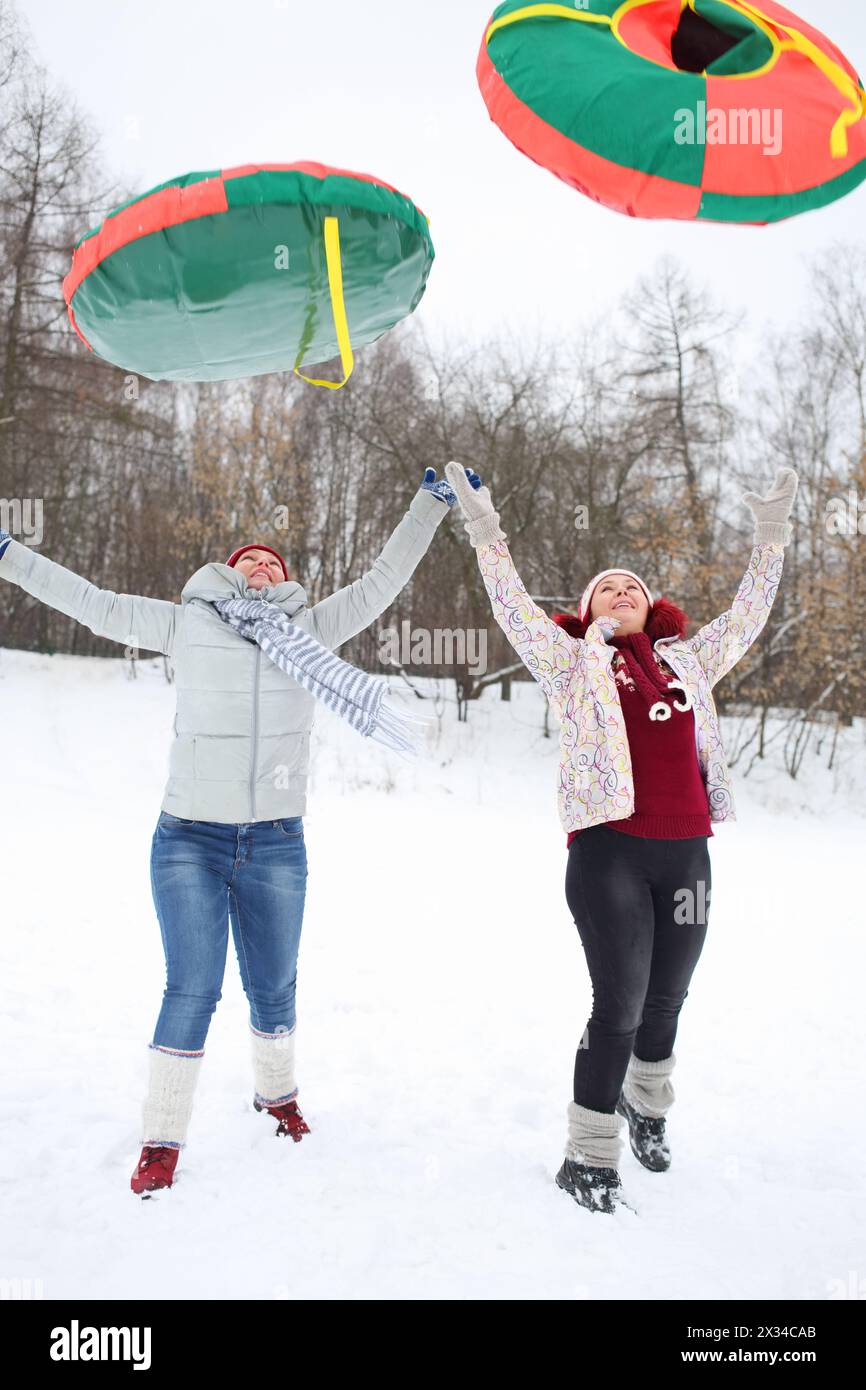 Zwei glückliche Frauen werfen am Wintertag im Freien helle Schneeräume auf Stockfoto