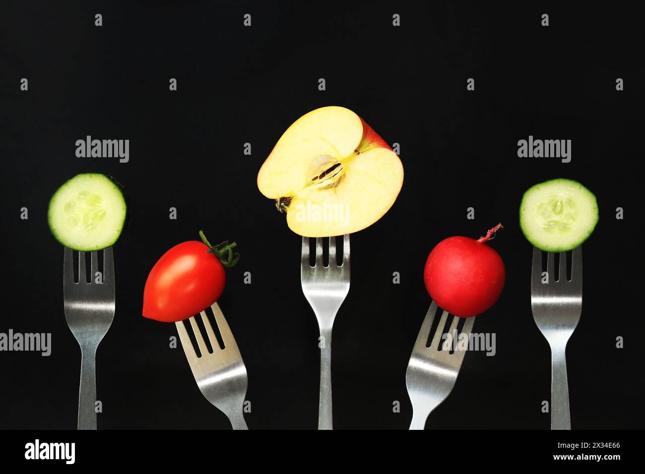 Ein halber Apfel, Tomate, Gurke und Rettich auf dunklem Hintergrund. Konzept für gesunde Ernährung. Frisches Gemüse und Obst in der Ernährung Stockfoto