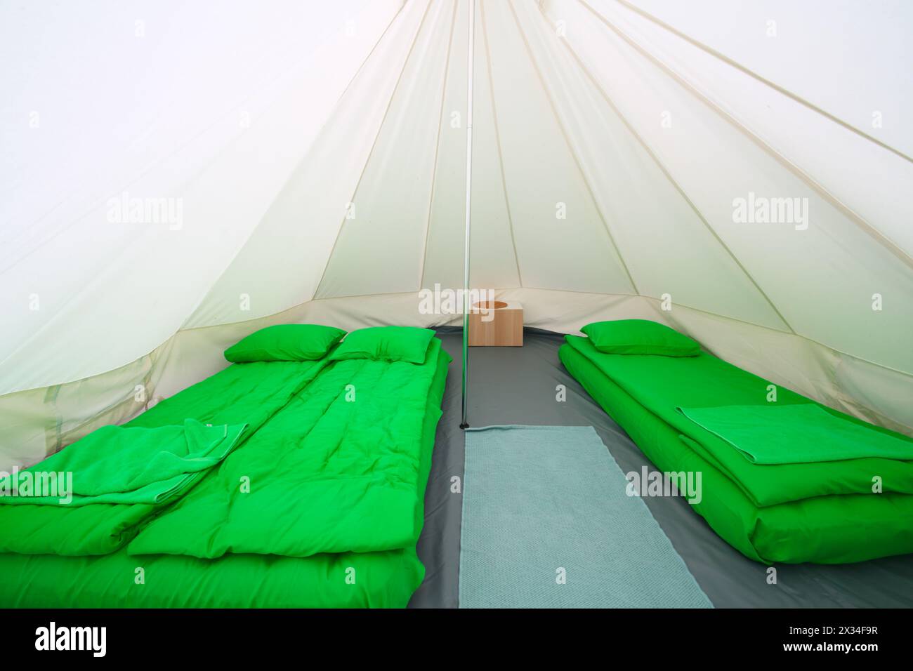 Weißes Innenzelt für Gäste mit grünen Schlafsäcken und aufblasbaren Matratzen Stockfoto