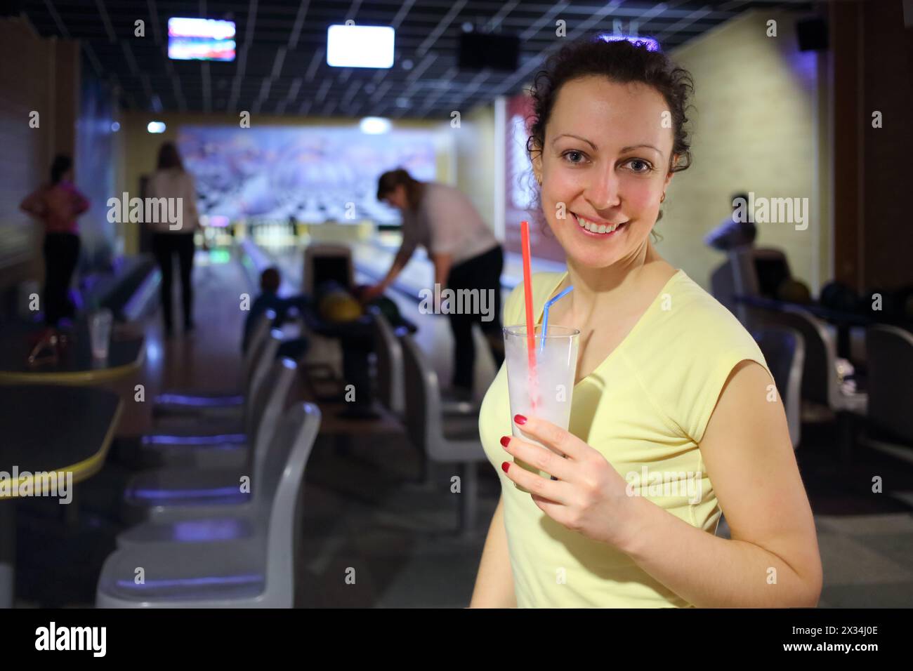 Porträt einer glücklichen Frau mit Milchshake in den Händen der Bowlinghalle Stockfoto