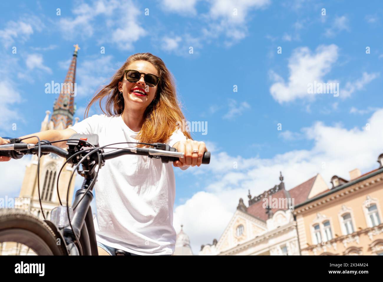 Unbeschwerte, glückliche junge Frau, die mit dem Fahrrad durch die Stadt reist. Aktiver Lifestyle im Sommer. Stockfoto
