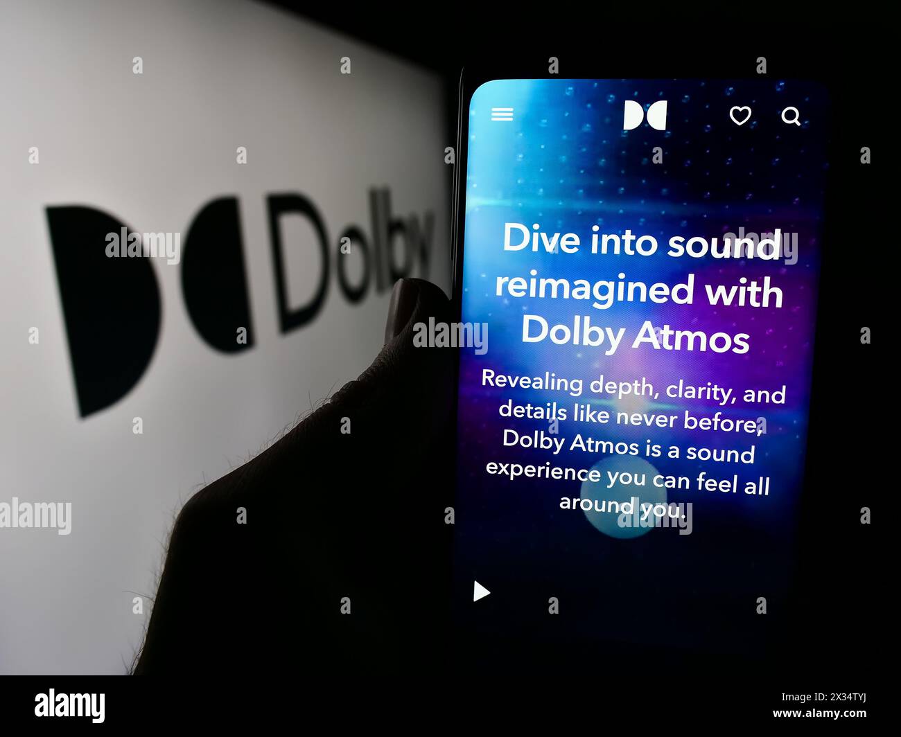 Person mit Smartphone und Webseite des Audiotechnologieunternehmens Dolby Laboratories Inc. Vor dem Logo. Konzentrieren Sie sich auf die Mitte des Telefondisplays. Stockfoto