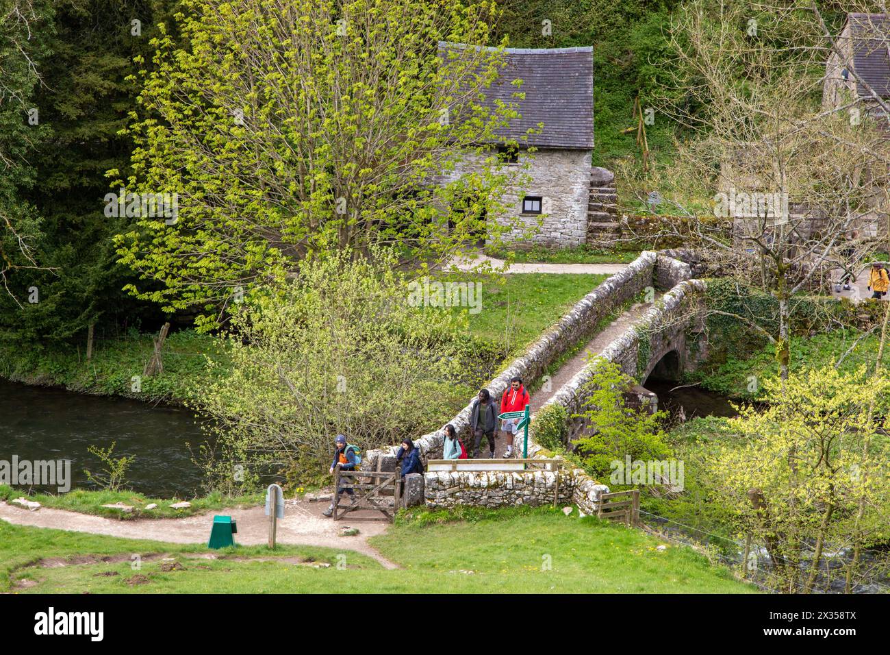 Wanderer und Wanderer überqueren VIATORS BRÜCKE über den Fluss Dove bei Milldale im English Peak District, der durch izaak Walton berühmt wurde Stockfoto