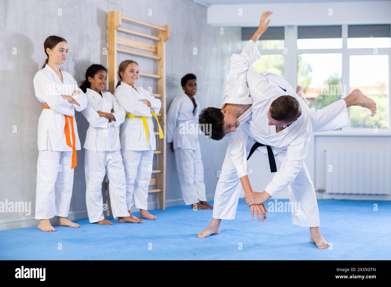 Judo-Trainer zeigt Kampftechniken im Sparring mit einem Jungen für eine Gruppe junger Athleten Stockfoto