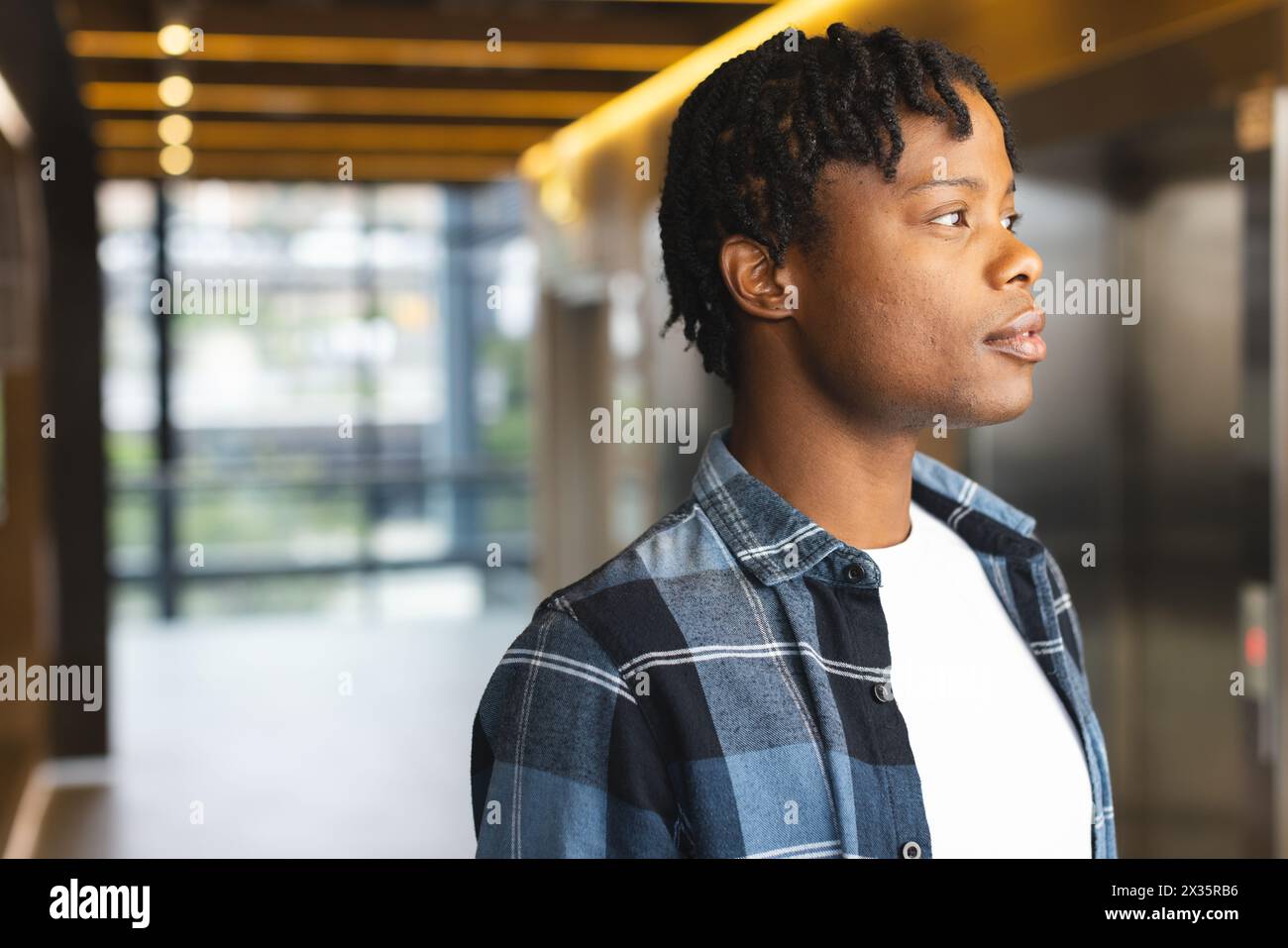 Afroamerikaner in kariertem Hemd steht im modernen Büro, Platz für Kopien Stockfoto
