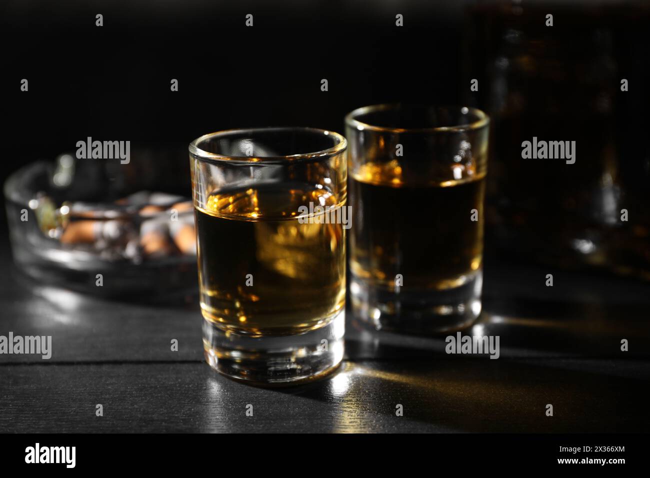 Alkoholsucht. Whiskey in Gläsern auf schwarzem Holztisch Stockfoto