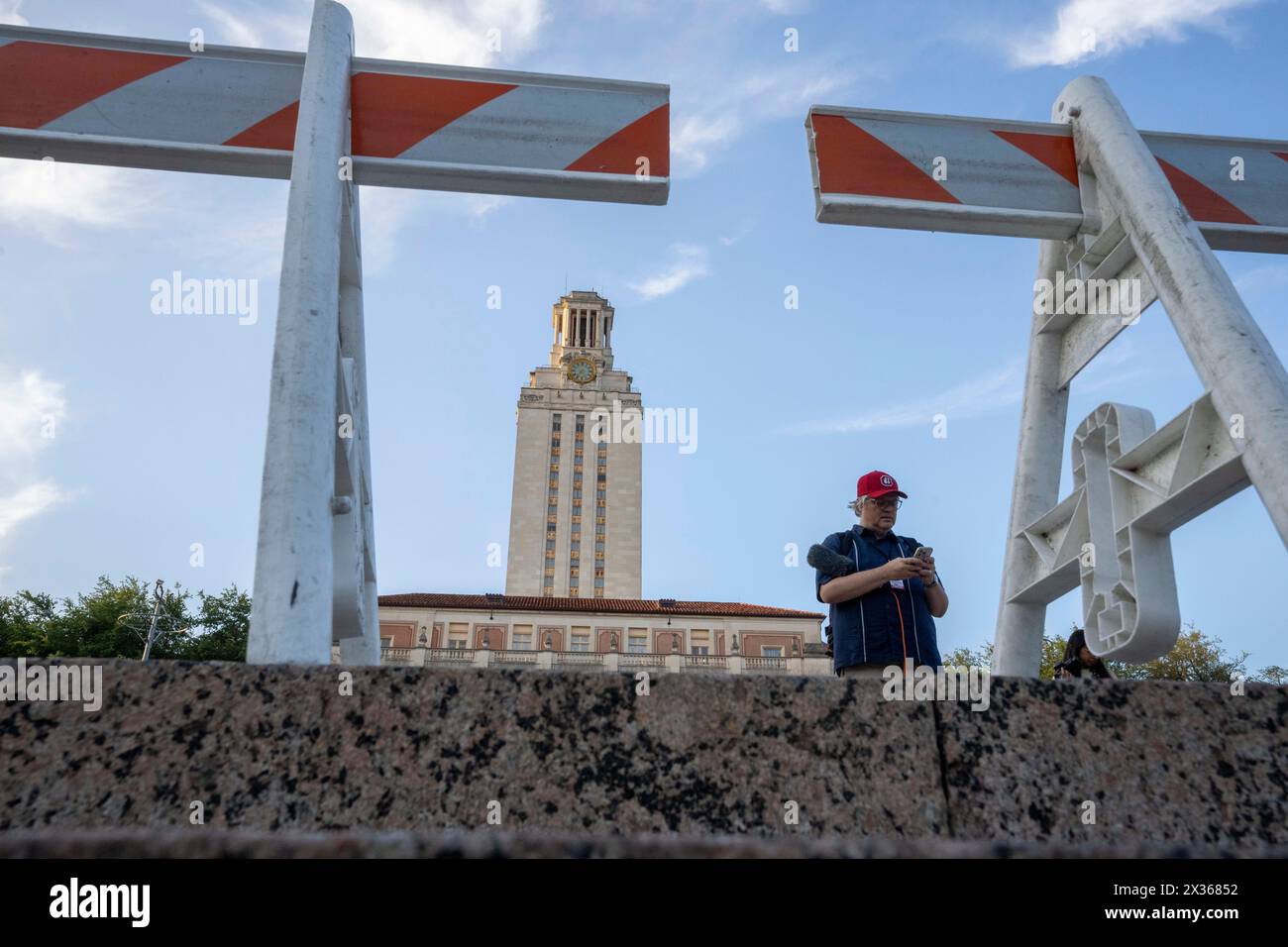 Austin Texas USA, 24. April 2024: Der Radioreporter Ben Philpott steht hinter einer Polizeibarrikade auf dem Campus der Universität von Texas, wo sich Anhänger des Palästinensischen Solidaritätskomitees (PSC) zu einem friedlichen Protest gegen den Krieg in Gaza am späten Abend vor dem UT Tower versammeln. Zu Beginn des Tages führte ein friedlicher pro-palästinensischer protestmarsch zu mehr als 50 Festnahmen auf dem Campus, nachdem Gouverneur Greg Abbott Truppen des texanischen Ministeriums für öffentliche Sicherheit (DPS) zum Tatort befahl, was die Spannungen während des Tages verschärfte. Quelle: Bob Daemmrich/Alamy Live News Stockfoto