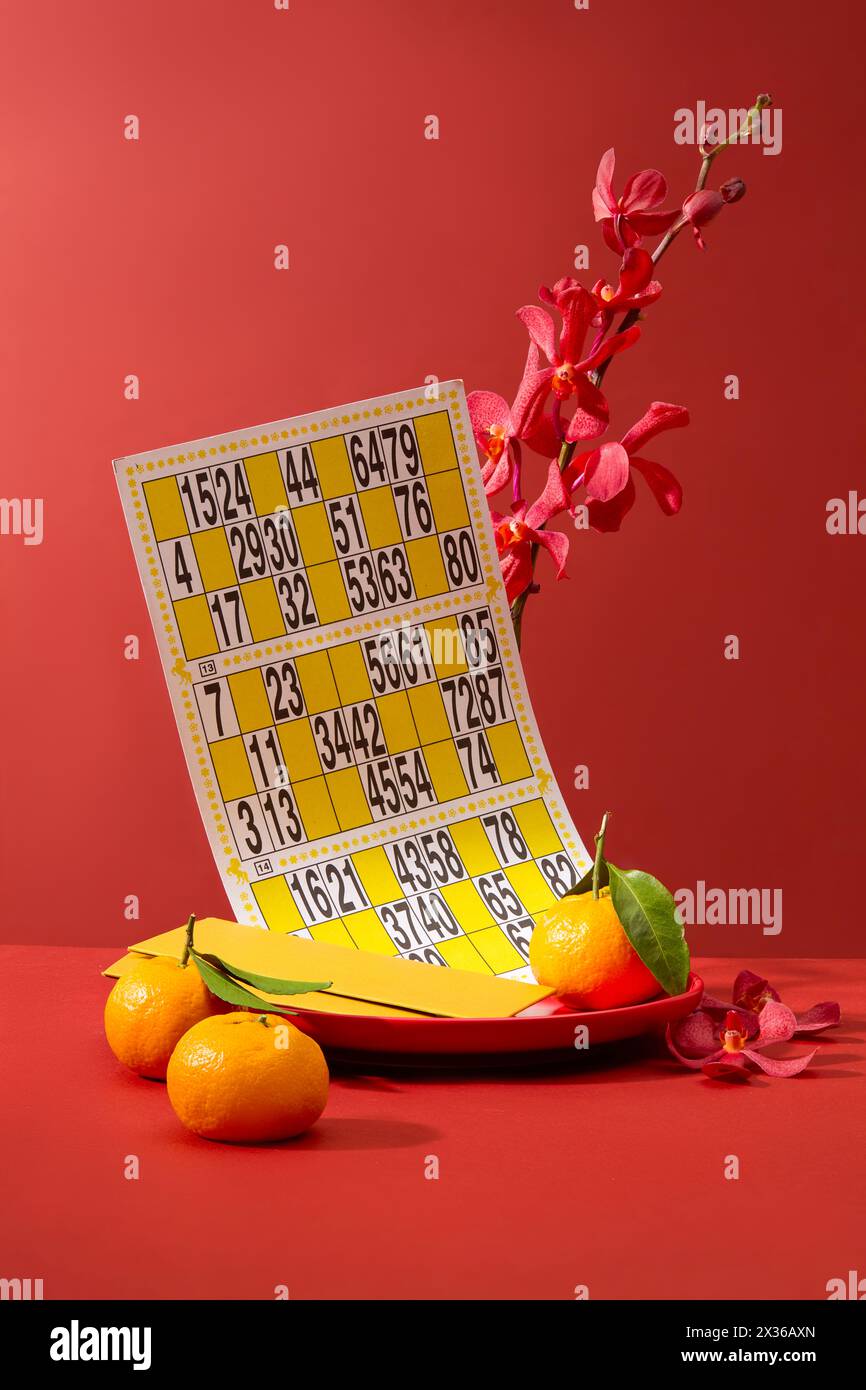 Eine Schüssel mit Umschlag, Mandarine und Bingo-Karte. Laut Sonnenkalender fällt das chinesische Neujahr an verschiedene Tage Stockfoto