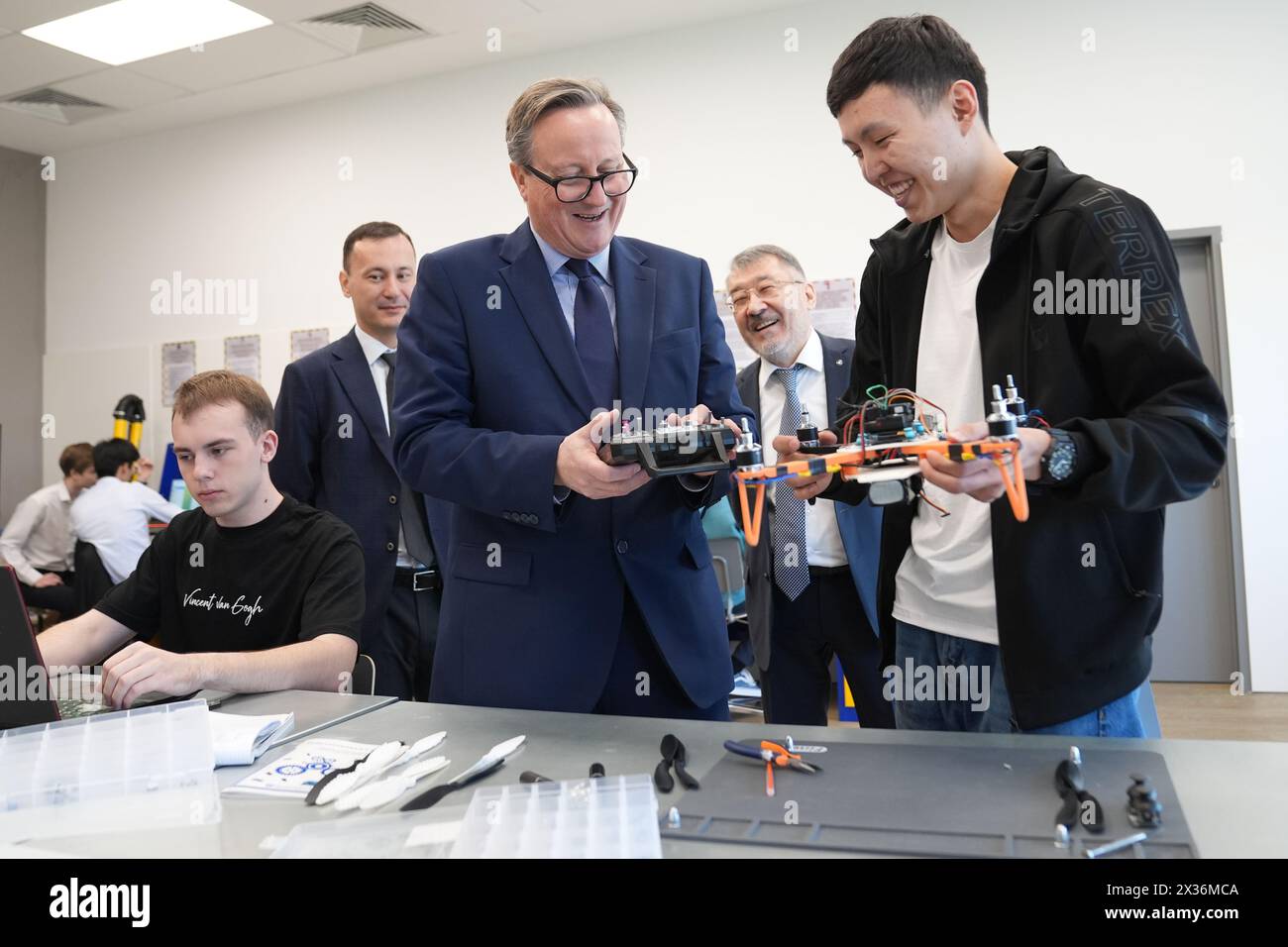 Außenminister Lord David Cameron betrachtet eine Drohne, die von einem Studenten (rechts) in einem Technologielabor hergestellt wurde, der in Englisch an der Astana IT University in Kasachstan während seiner fünftägigen Tour durch Zentralasien unterrichtet wird. Bilddatum: Donnerstag, 25. April 2024. Stockfoto