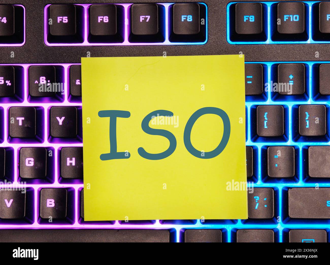 Das Konzept der ISO-Qualitätskontrollzertifizierung. Abkürzung ISO es ist auf einem gelben Aufkleber auf der beleuchteten Tastatur angegeben Stockfoto