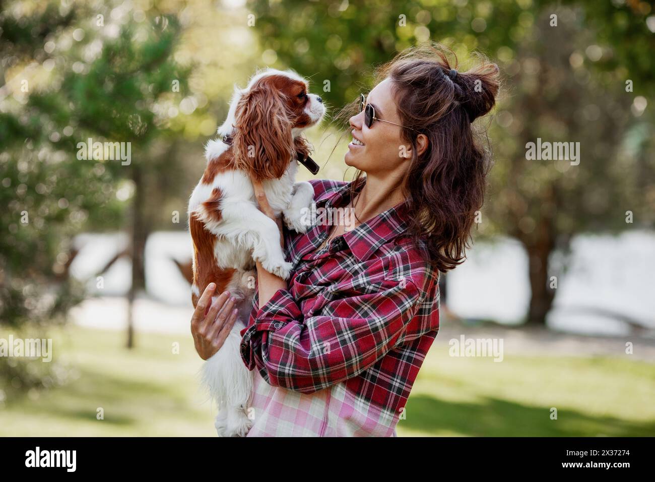 Die Haustierinhaberin hält ihren Hund liebevoll im Freien, liebt und verbindet sich mit dem Haustier. Stockfoto