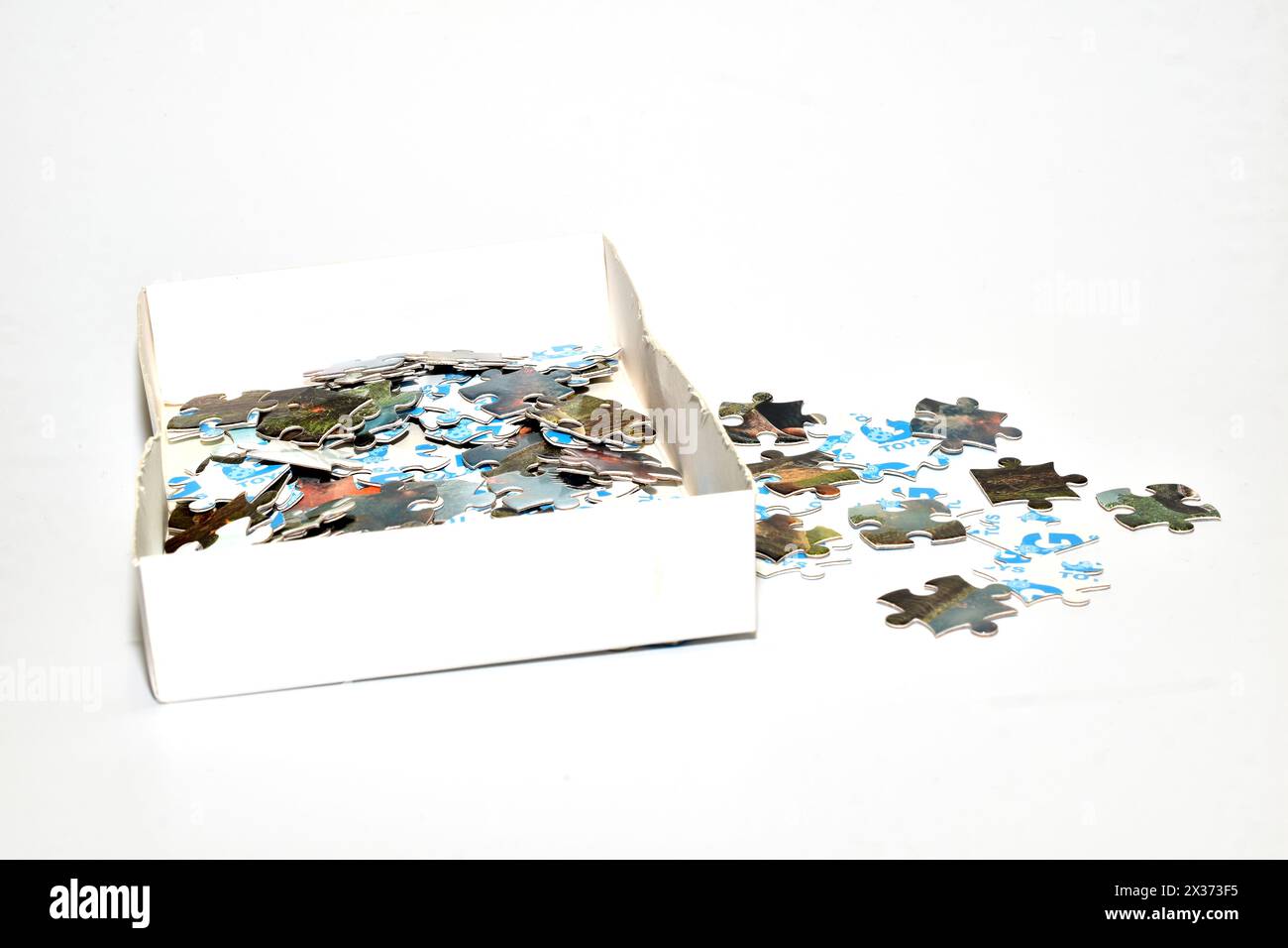 Auf dem Bild befindet sich eine Schachtel mit Puzzles und mehreren Puzzleteilen, die neben der Schachtel liegen. Stockfoto
