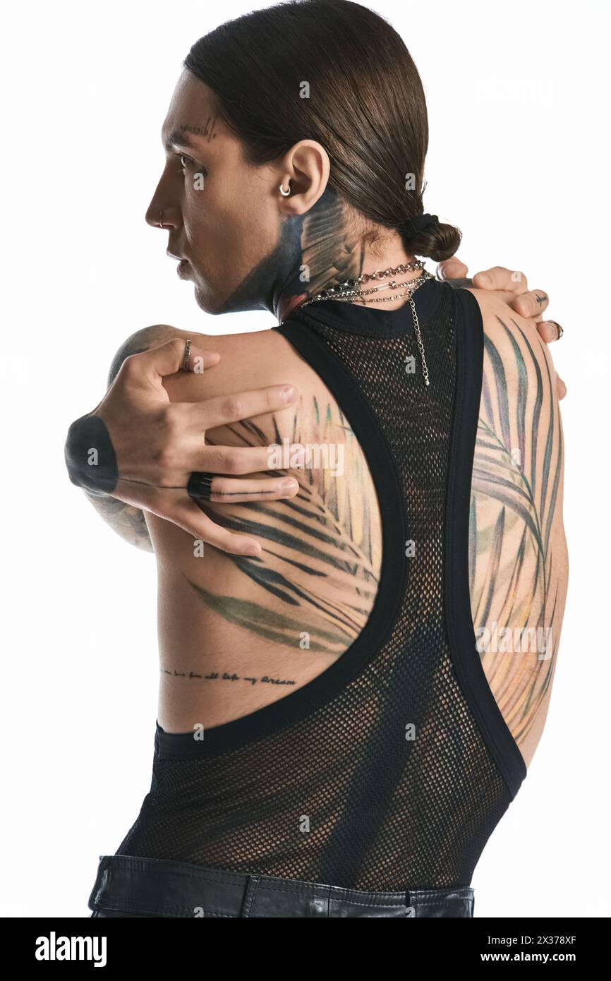 Ein junger Mann mit einem detailgetreuen Tattoo auf dem Rücken, das Kunst und Selbstausdruck in einem Studio zeigt. Stockfoto
